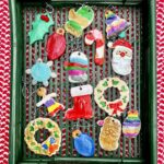 Painted salt-dough christmas ornaments on a green tray on red and white cloth